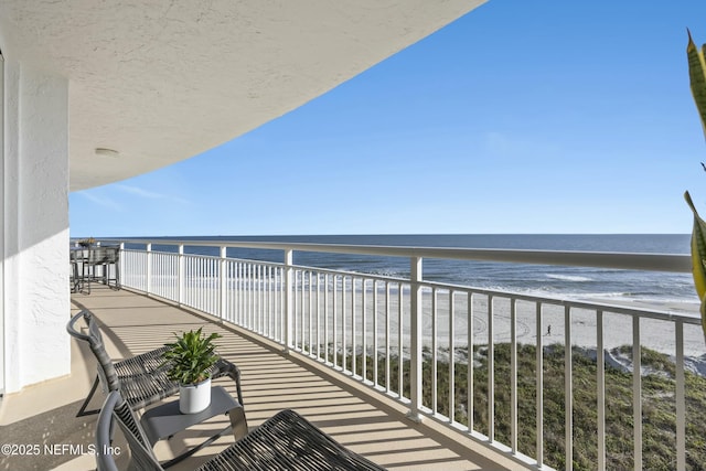 balcony featuring a beach view and a water view