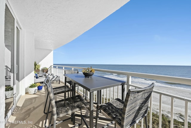 balcony featuring a water view and a beach view