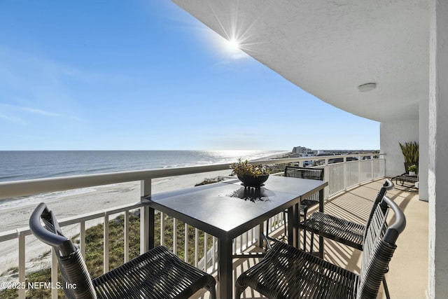 balcony with a water view and a view of the beach