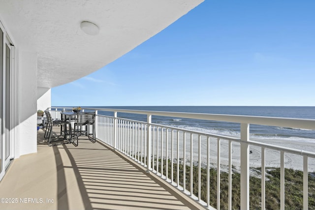 balcony with a water view and a beach view