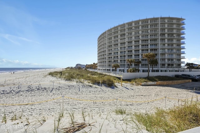 view of building exterior with a beach view and a water view