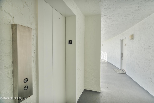 hallway featuring concrete floors and elevator