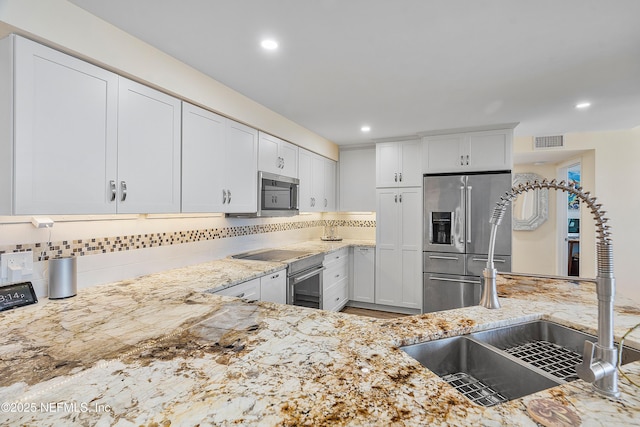 kitchen featuring white cabinetry, sink, decorative backsplash, light stone counters, and stainless steel appliances