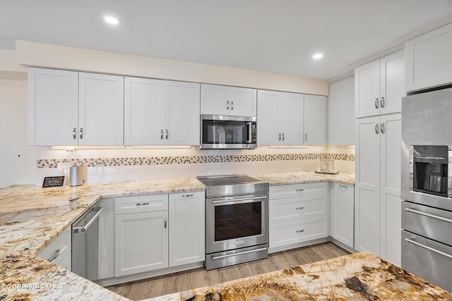 kitchen with stainless steel appliances, white cabinetry, tasteful backsplash, and light wood-type flooring