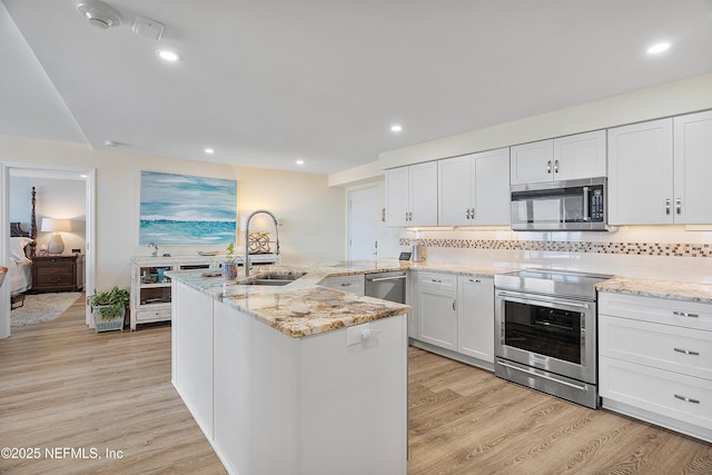 kitchen with white cabinetry, stainless steel appliances, sink, and light hardwood / wood-style flooring