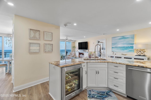 kitchen with dishwasher, white cabinets, beverage cooler, light stone counters, and light hardwood / wood-style floors