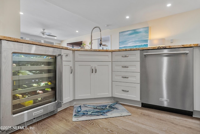 kitchen featuring white cabinetry, dishwasher, wine cooler, light stone counters, and light hardwood / wood-style flooring