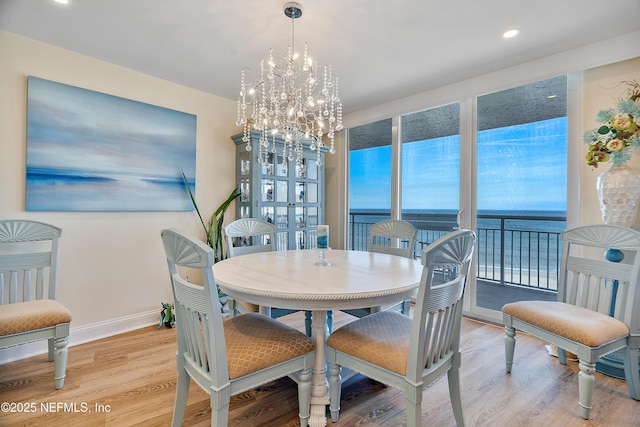 dining room with light hardwood / wood-style floors, a chandelier, and a water view