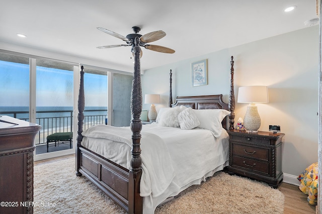 bedroom featuring ceiling fan, a water view, access to outside, and light wood-type flooring