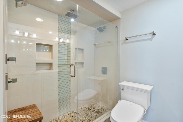 bathroom featuring a shower with door and toilet