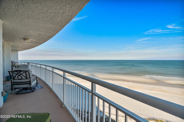 balcony with a water view and a view of the beach