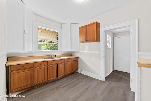 kitchen featuring a textured ceiling, light wood-type flooring, and sink