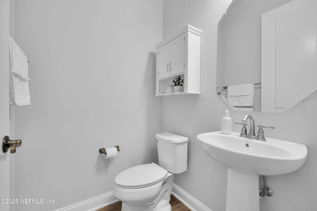 bathroom with wood-type flooring, toilet, and sink