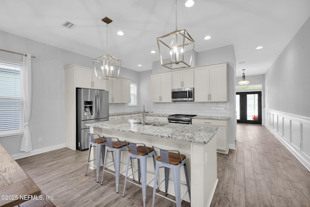 kitchen featuring white cabinets, appliances with stainless steel finishes, a kitchen island with sink, and sink