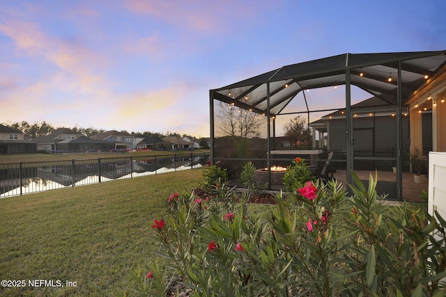 yard at dusk with glass enclosure and a water view