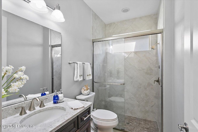 bathroom featuring vanity, toilet, and a shower with shower door