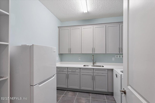 kitchen with gray cabinetry, sink, white refrigerator, a textured ceiling, and dark tile patterned flooring