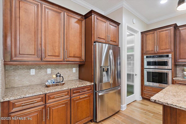 kitchen featuring light stone countertops, ornamental molding, appliances with stainless steel finishes, tasteful backsplash, and light hardwood / wood-style floors