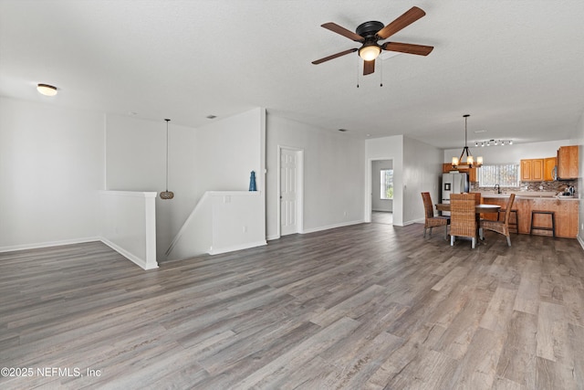 living room with ceiling fan with notable chandelier, sink, a textured ceiling, and light hardwood / wood-style flooring