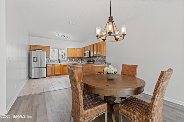 dining room with a notable chandelier, light hardwood / wood-style floors, sink, and a textured ceiling