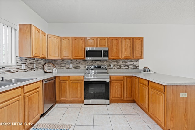 kitchen featuring a textured ceiling, tasteful backsplash, light tile patterned flooring, kitchen peninsula, and stainless steel appliances