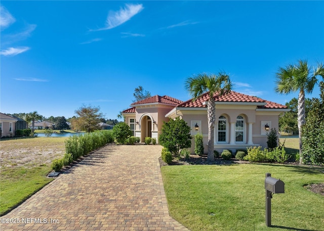 mediterranean / spanish-style home with a water view and a front lawn