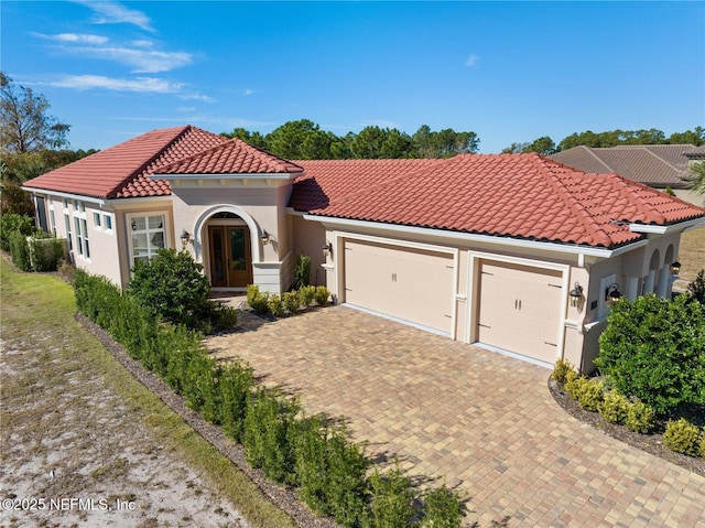 mediterranean / spanish house with a garage and french doors