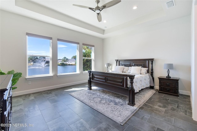 bedroom featuring a tray ceiling, ceiling fan, and a water view