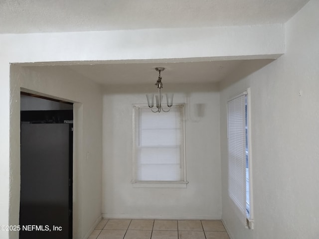 unfurnished dining area with light tile patterned flooring and an inviting chandelier