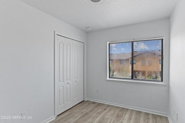 unfurnished bedroom with a closet, a textured ceiling, and light wood-type flooring