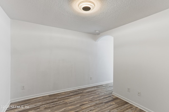 empty room featuring dark wood-type flooring and a textured ceiling