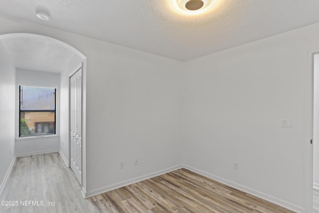 unfurnished room featuring a textured ceiling and light wood-type flooring