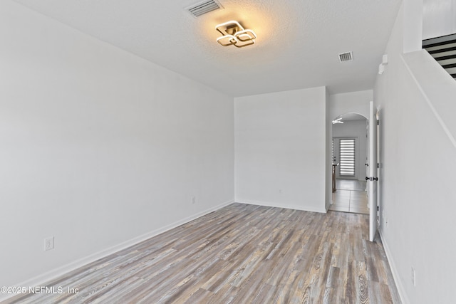 empty room with light hardwood / wood-style floors and a textured ceiling