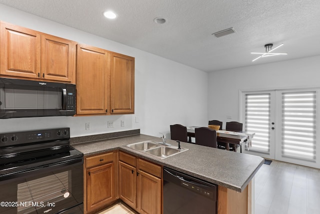 kitchen with kitchen peninsula, sink, black appliances, and a textured ceiling