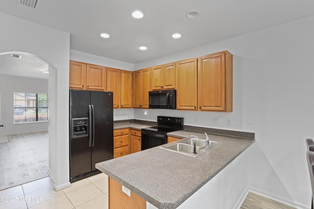 kitchen featuring kitchen peninsula, sink, light tile patterned floors, and black appliances