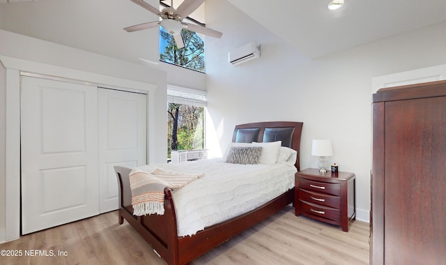 bedroom with ceiling fan, light hardwood / wood-style flooring, a wall mounted air conditioner, and a closet