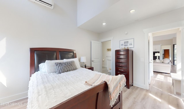 bedroom with light hardwood / wood-style flooring and an AC wall unit