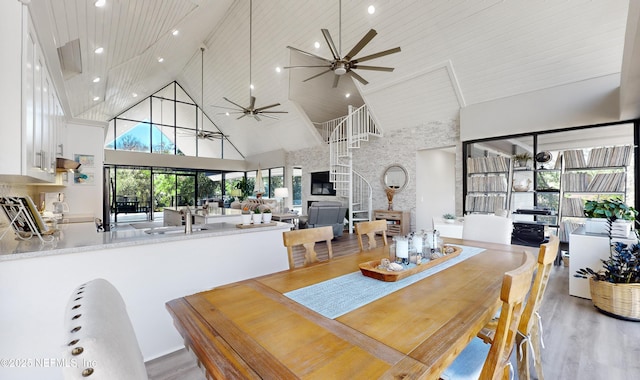 dining space with sink, ceiling fan, light hardwood / wood-style flooring, high vaulted ceiling, and wood ceiling