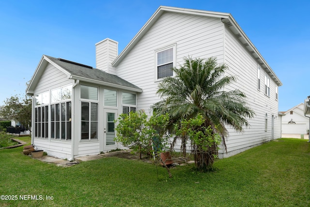 rear view of property featuring a lawn and a sunroom