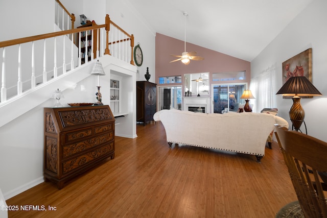 living room with ceiling fan, built in features, high vaulted ceiling, and hardwood / wood-style flooring