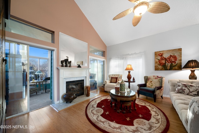 living room featuring a fireplace, ceiling fan, hardwood / wood-style floors, and high vaulted ceiling