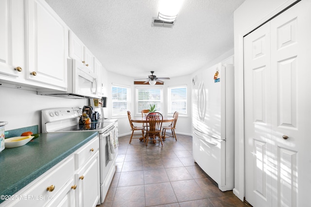 kitchen with a textured ceiling, white appliances, dark tile patterned floors, ceiling fan, and white cabinetry