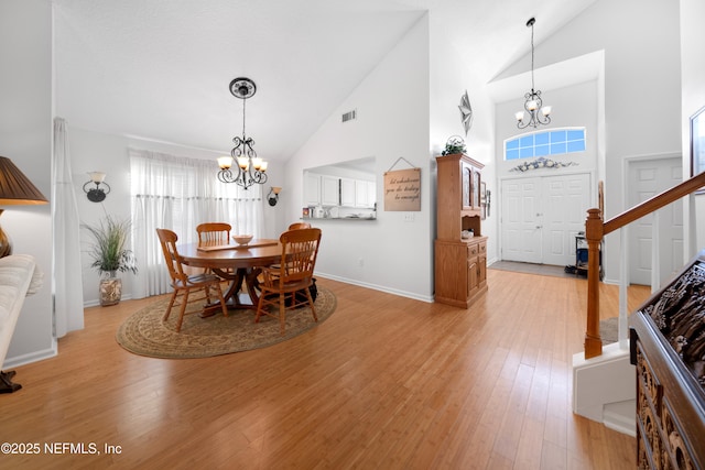 dining area with light hardwood / wood-style floors, high vaulted ceiling, and a notable chandelier