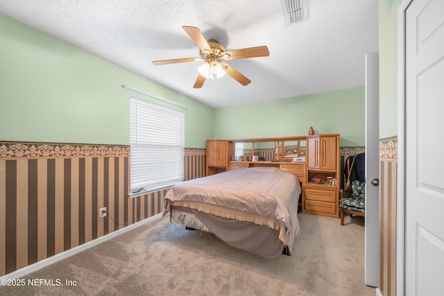 bedroom with ceiling fan, a textured ceiling, and light carpet