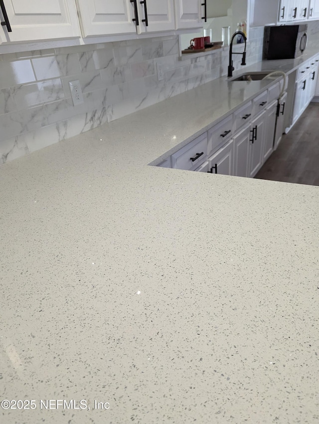 kitchen featuring backsplash, light stone counters, and white cabinets