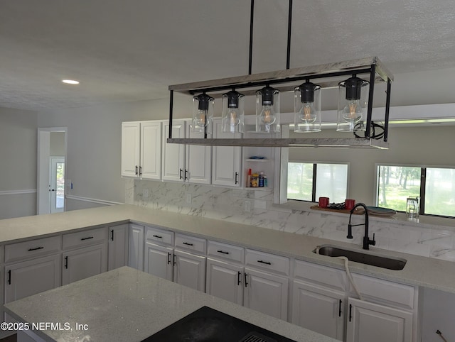 kitchen featuring light stone counters, white cabinetry, and sink