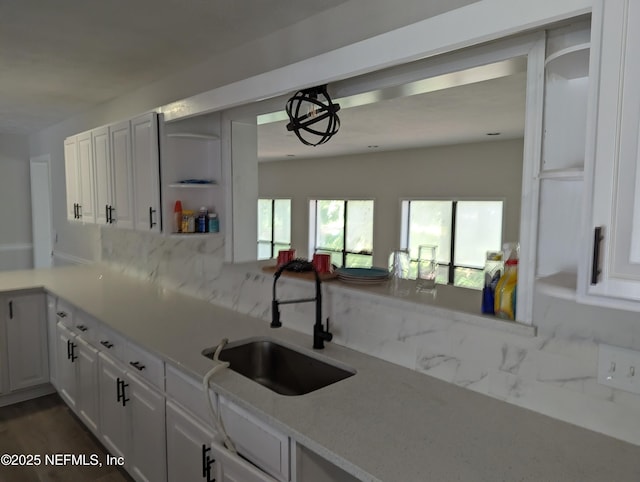 kitchen with dark wood-type flooring, sink, decorative backsplash, light stone countertops, and white cabinetry