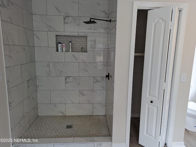 bathroom with toilet and a tile shower