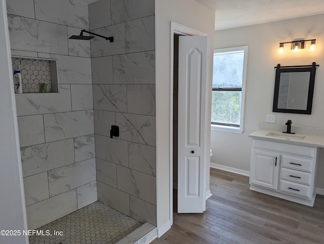 bathroom featuring hardwood / wood-style floors, vanity, and tiled shower