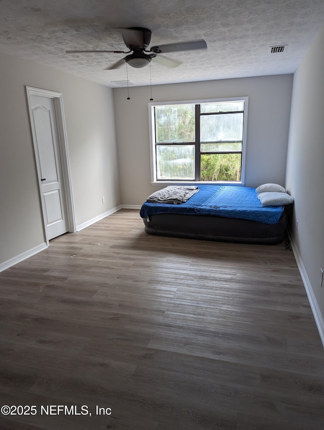 unfurnished bedroom with ceiling fan, dark hardwood / wood-style floors, and a textured ceiling